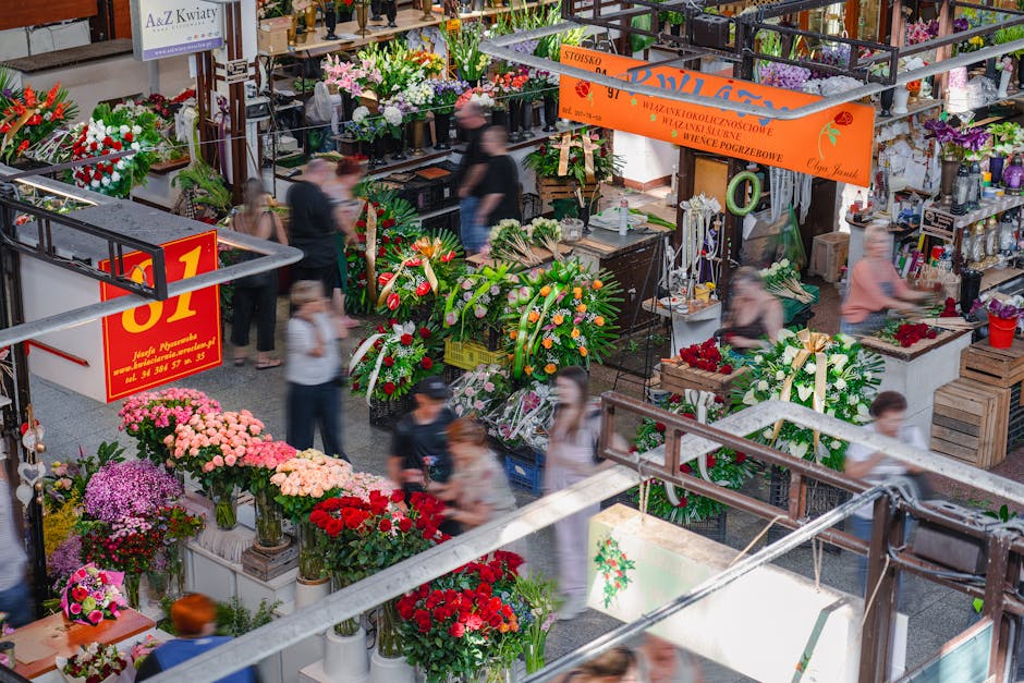 A busy flower market at an indoor floral shop near Temple station and Embankment, featuring an array of vibrant and fresh floral arrangements. Prominent are bouquets of pink, red, and purple chrysanth